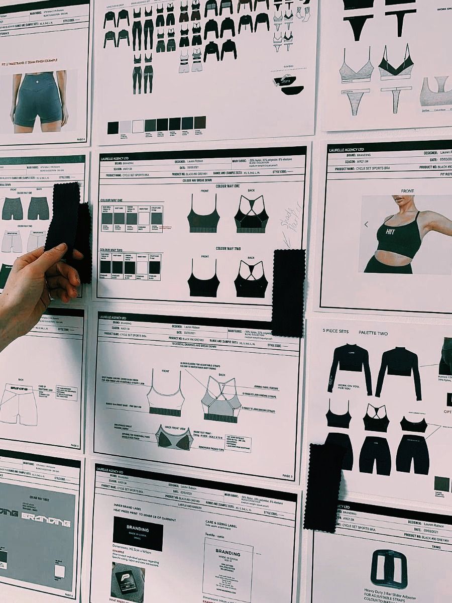 Person's hand adjusting a design board with sketches and product mockups of activewear, clipped to a wall.