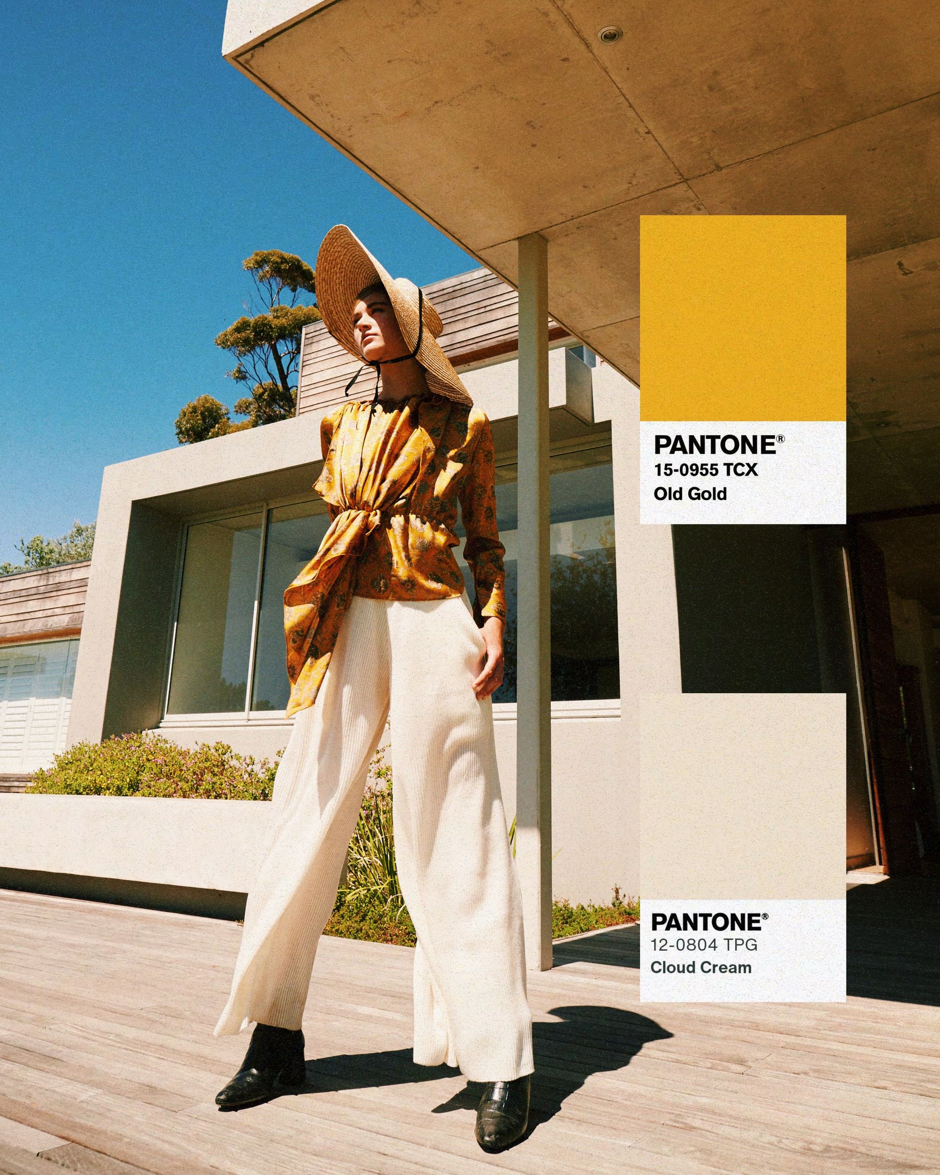 Woman in yellow top and white pants stands outside a modern building. A Pantone color swatch of 