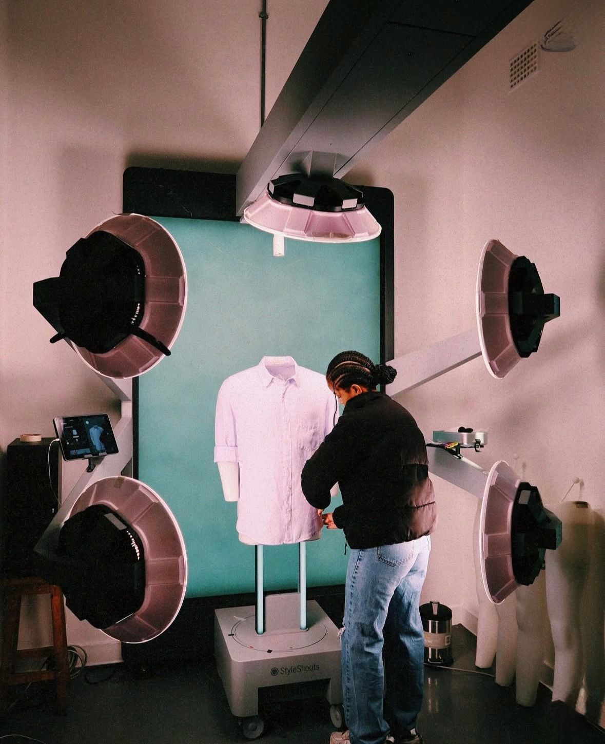 Person adjusting shirt on a mannequin surrounded by studio lights.