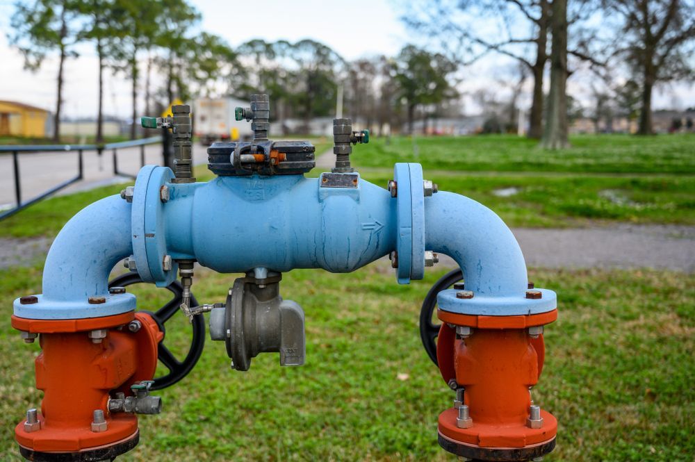 A Blue Industrial Backflow Prevention Device on Orange Vertical Pipes — PlumbPlus in Kawana, QLD