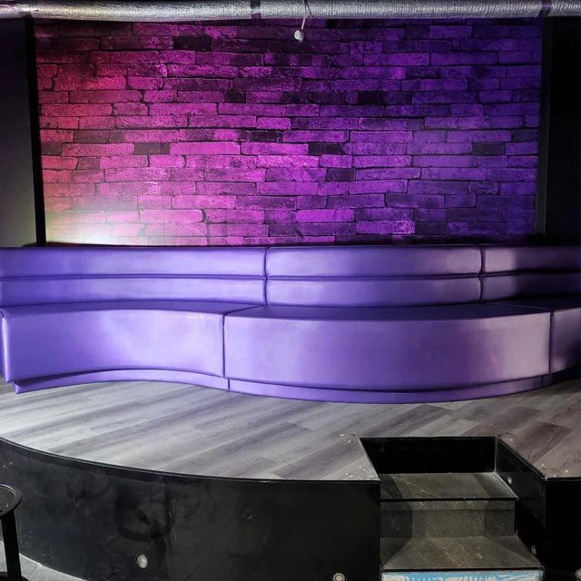 A Purple Couch is Sitting in Front of a Brick Wall — Coastal Coverings In Smithfield, QLD