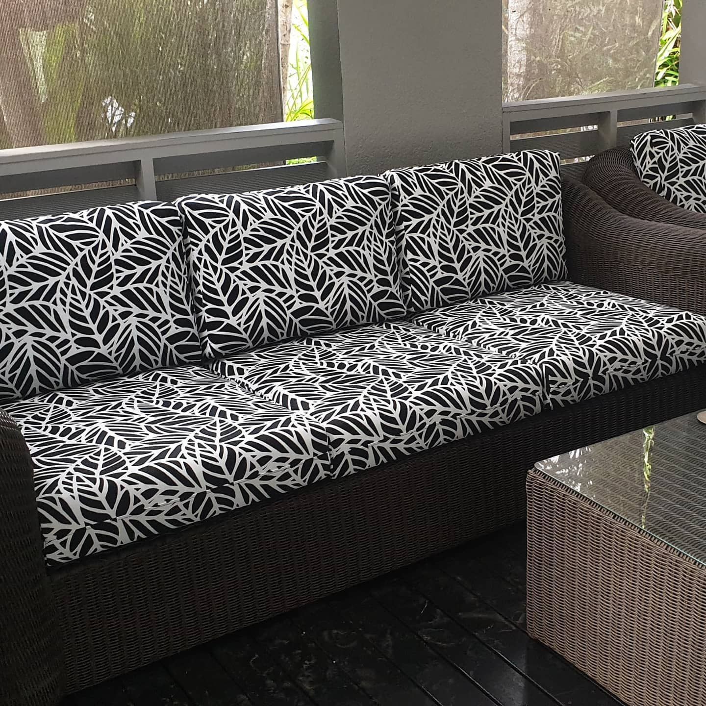 A Black and White Couch is Sitting on a Porch Next to a Table — Coastal Coverings In Smithfield, QLD