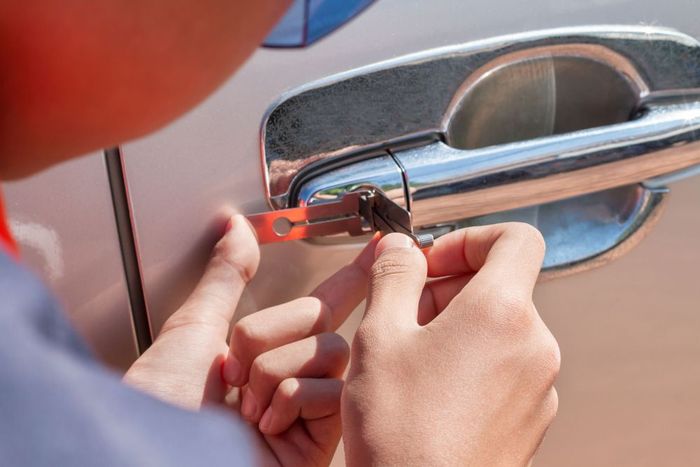 A person is unlocking a car door with a pick