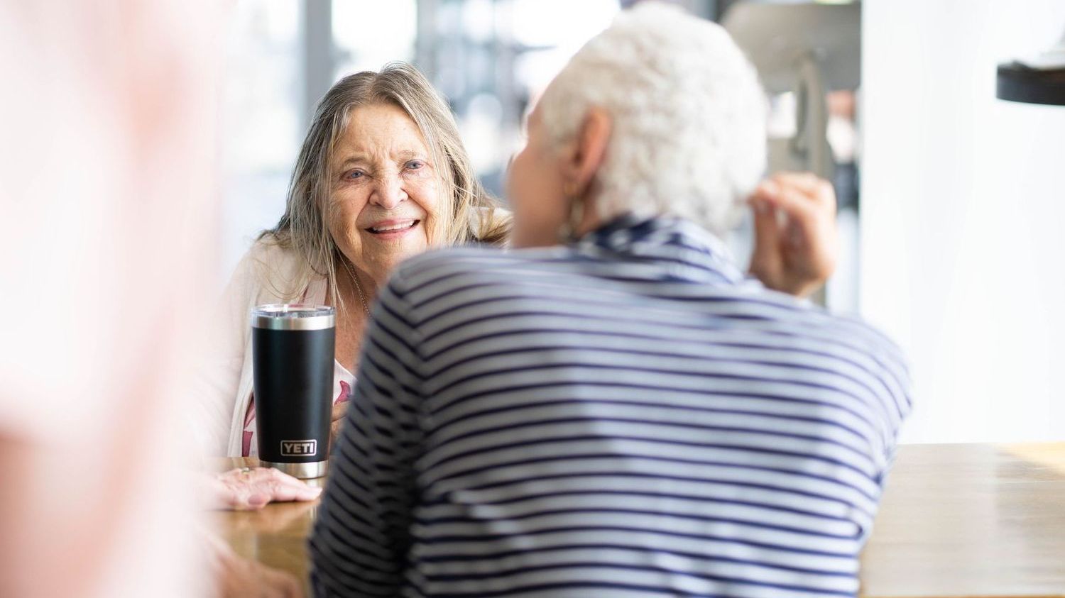 A man and a woman are sitting at a table talking to each other.