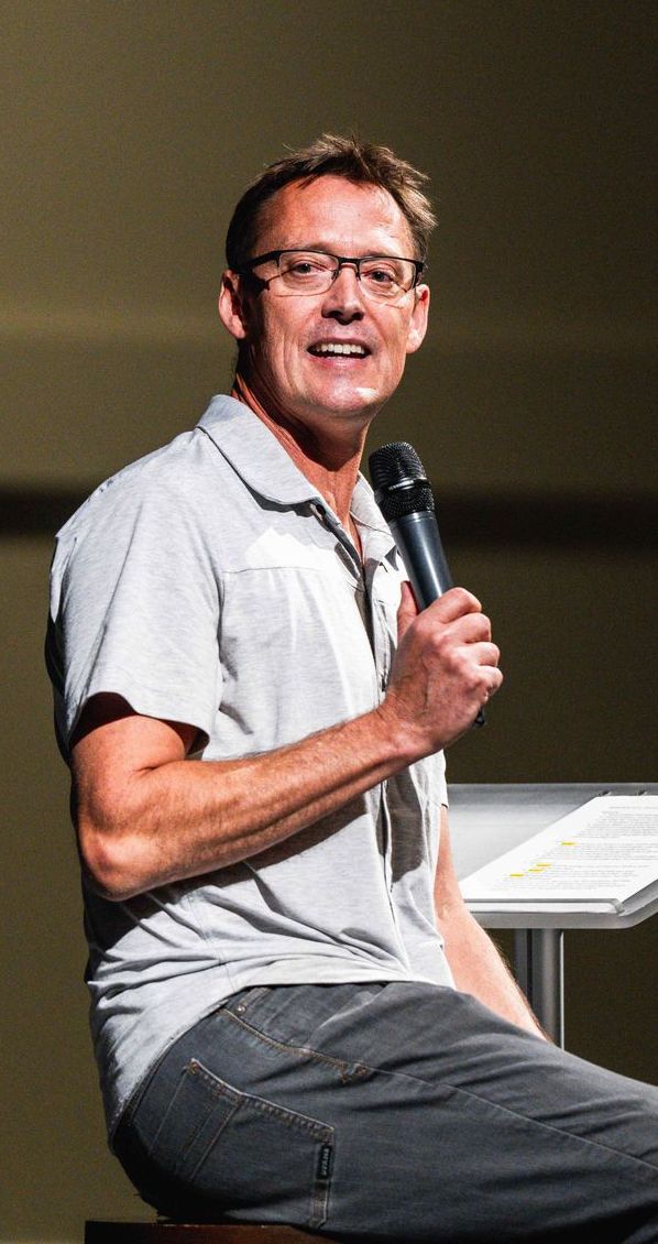 A man is sitting at a table holding a microphone.