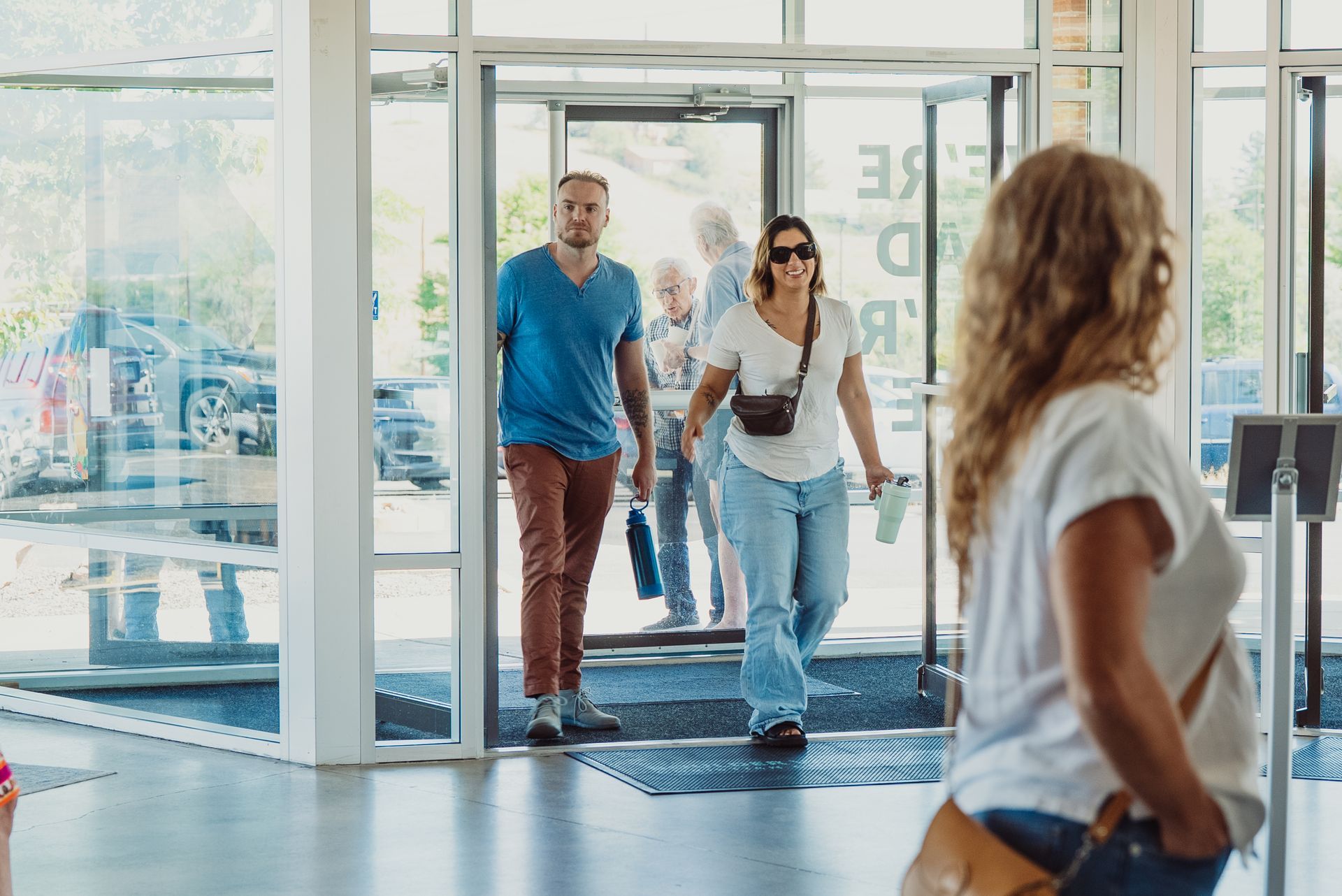 A group of people are walking through a hallway with a sign on the wall that says us till evermore delones.