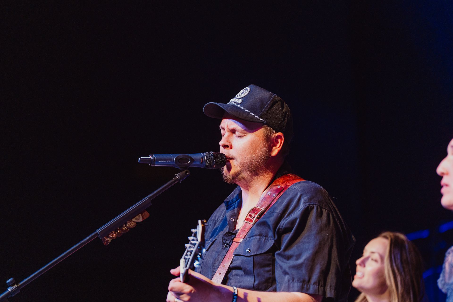 A man is singing into a microphone while playing a keyboard on stage.