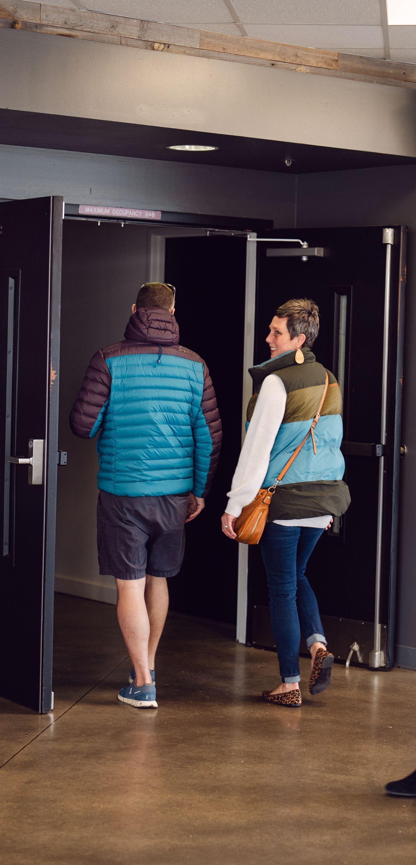 A man and a woman are walking through a doorway.