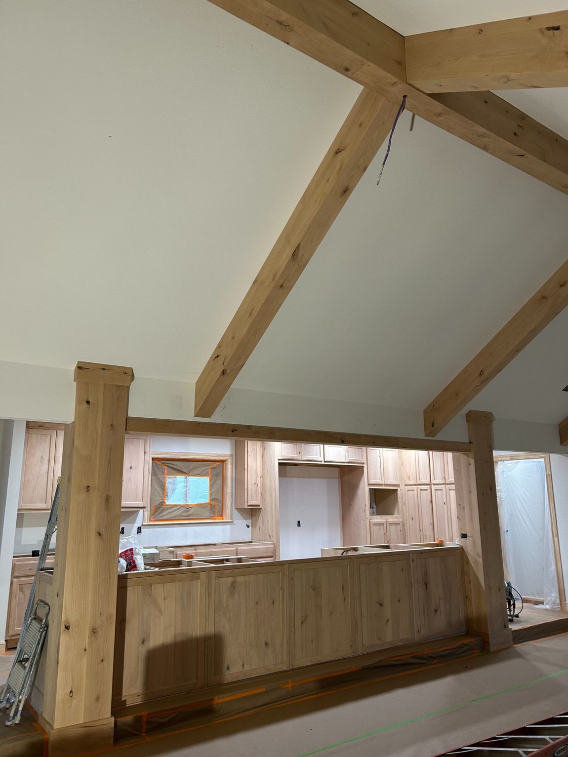 Wooden interior room with exposed beams, a long counter, and unfinished walls and trim