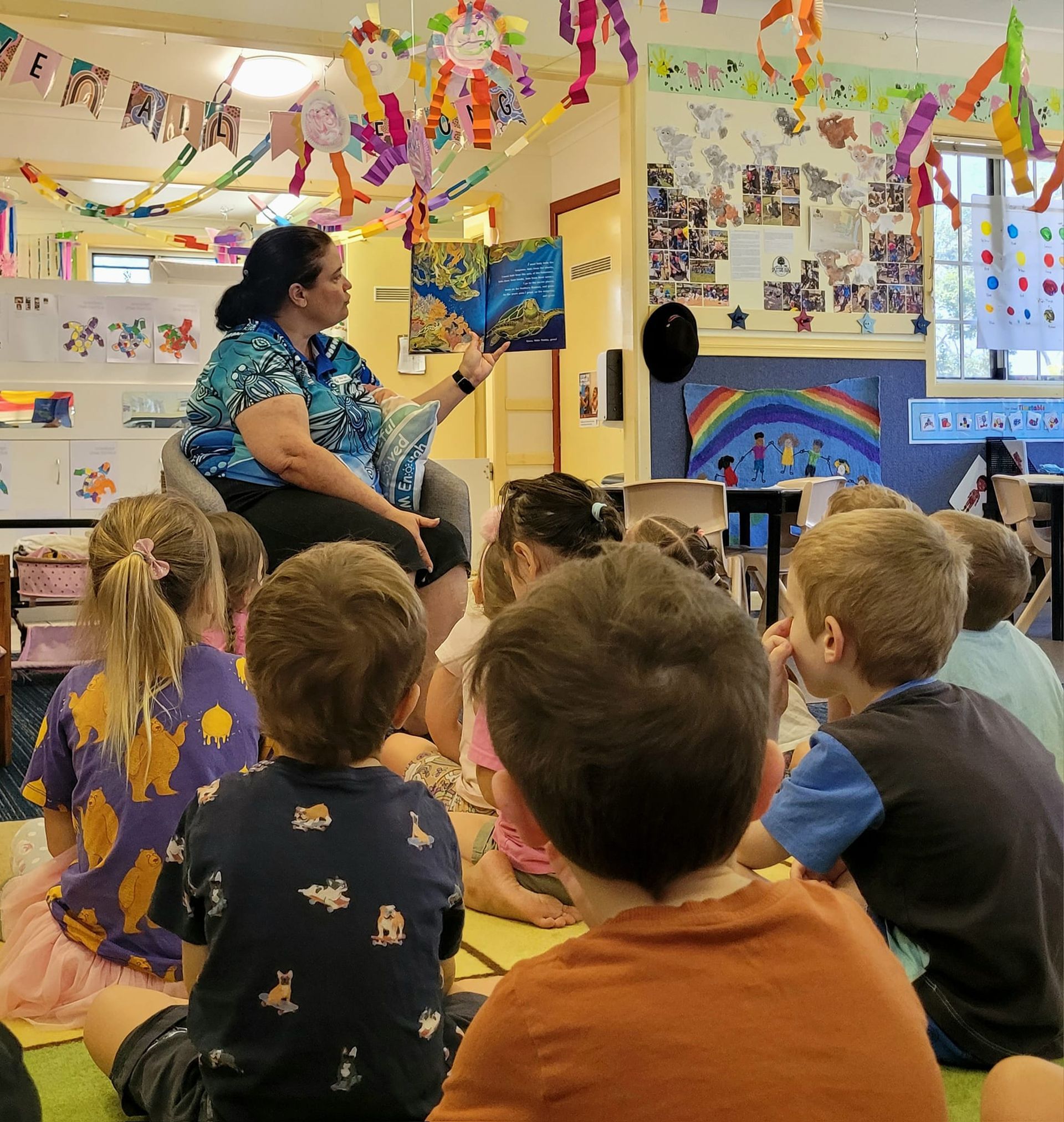 A woman is reading a book to a group of children