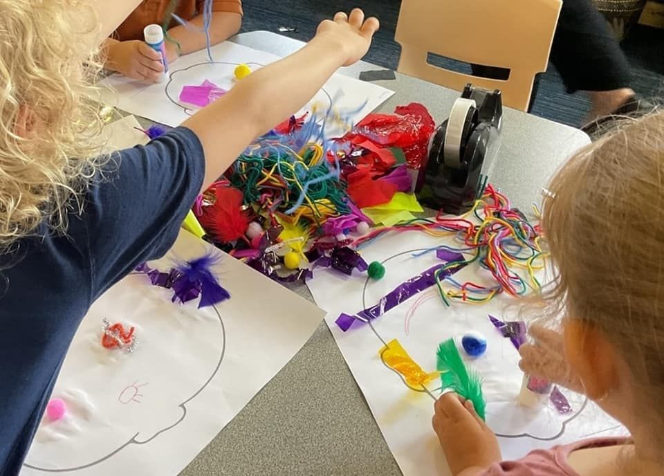 A group of children are sitting at a table making crafts.