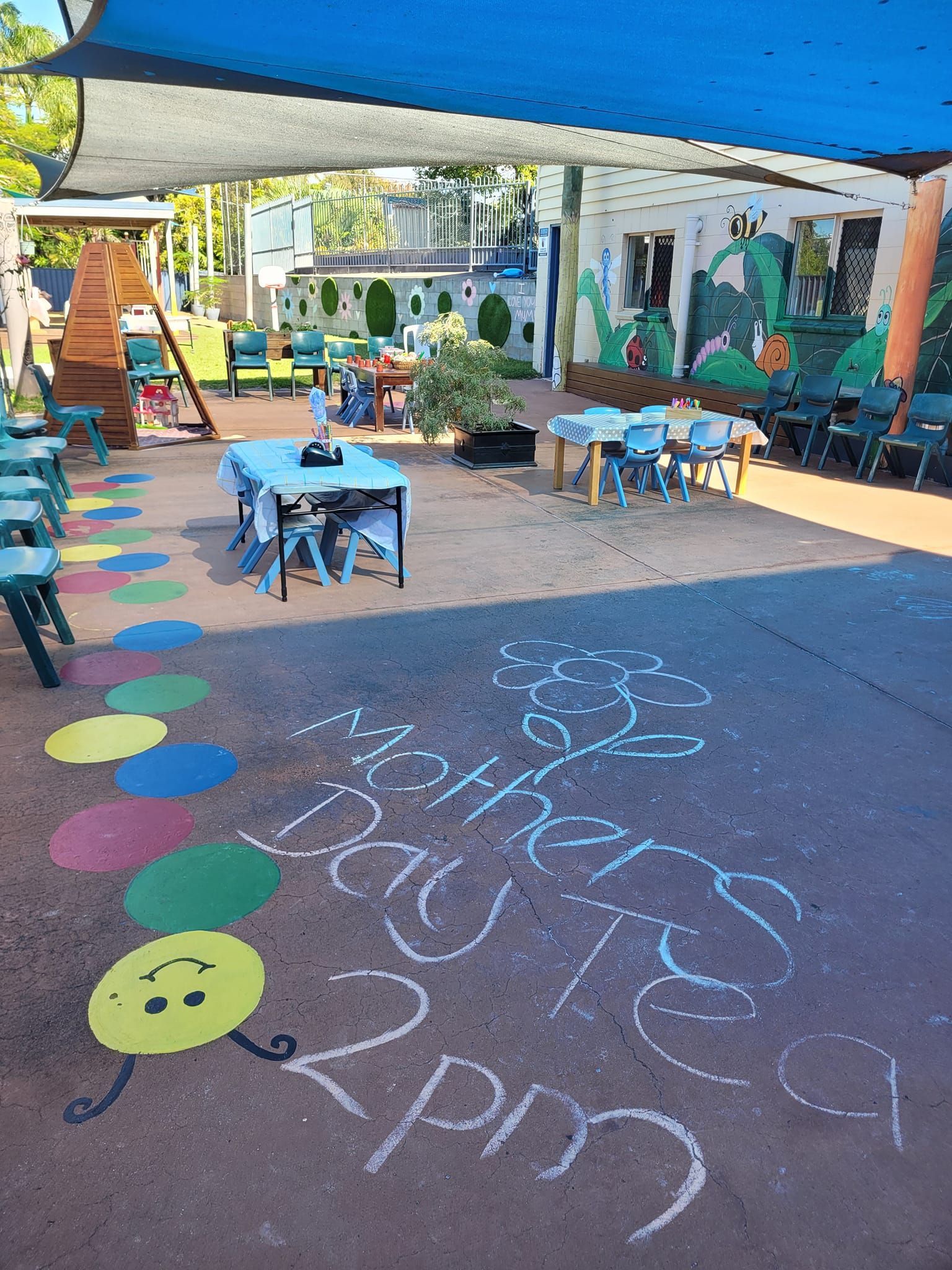 A chalk drawing of a caterpillar is on the ground in a playground.