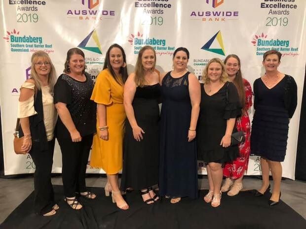 A group of women standing in front of a wall that says excellence awards