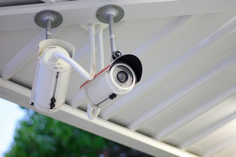 Two white security cameras mounted on a white ceiling, facing downward.