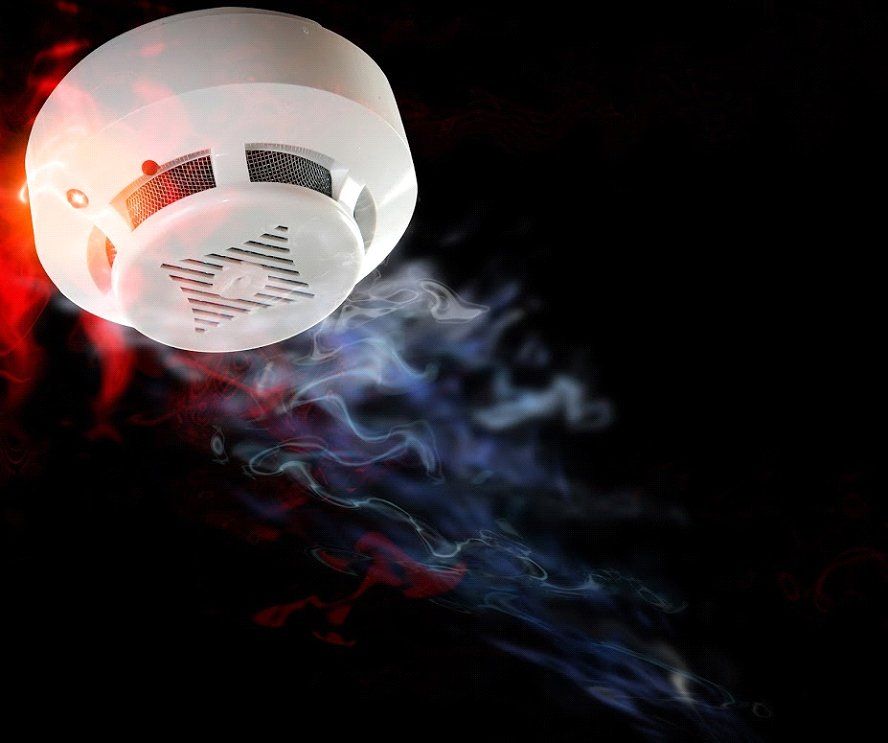 Smoke detector with red and blue smoke billowing from it against a black background.