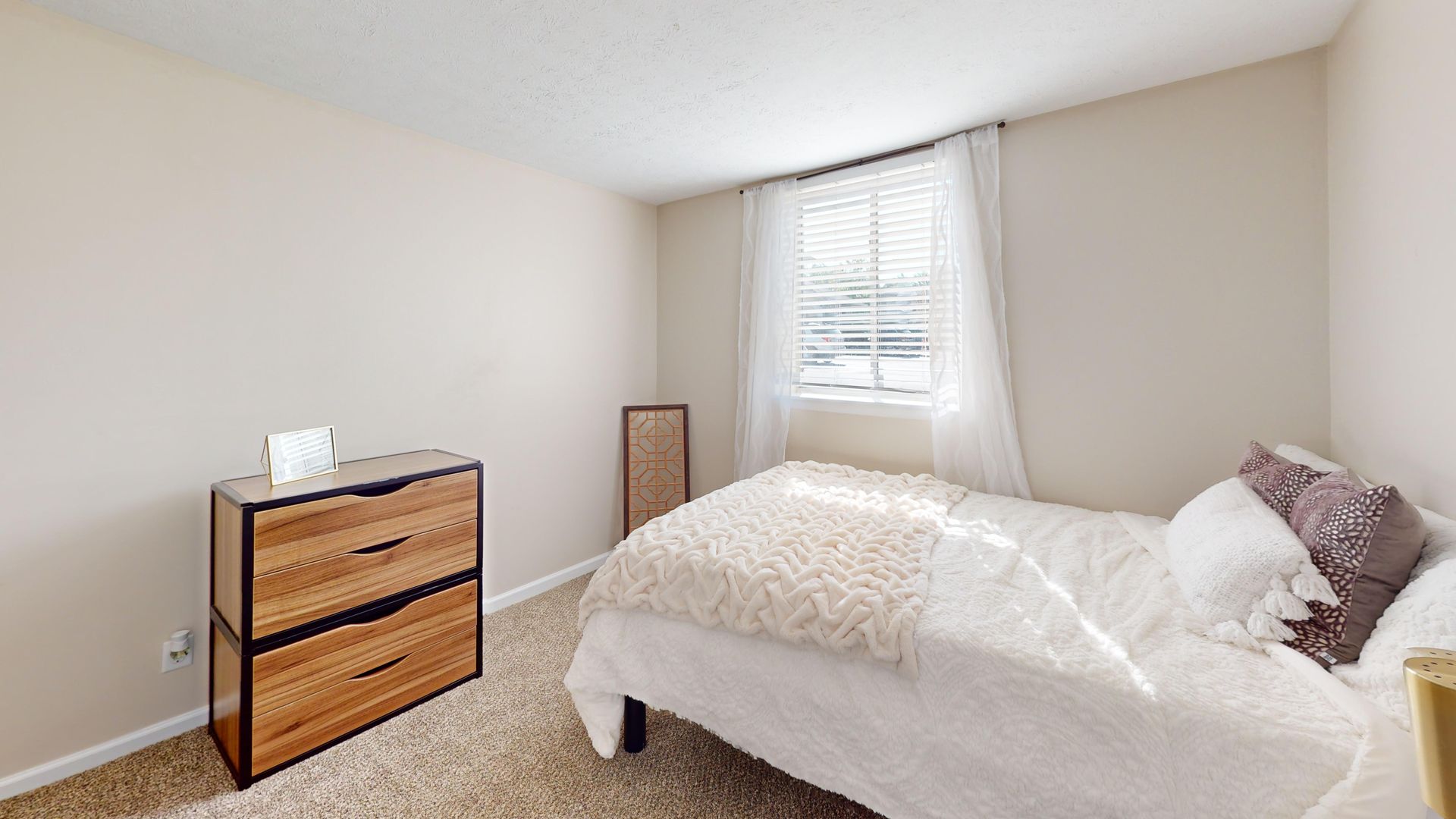 Photo of one bedroom apartment. White bed with dresser against the wall