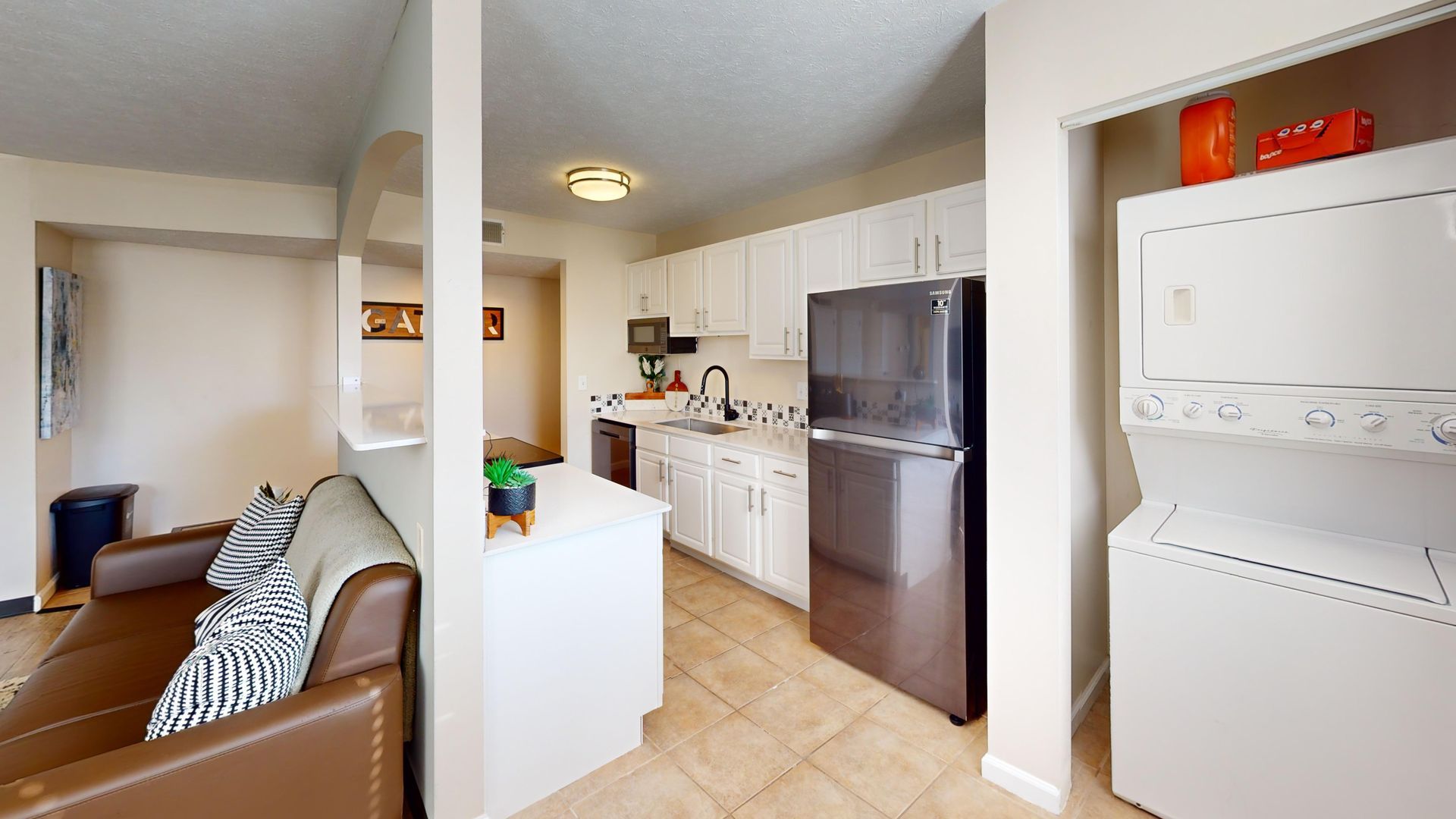Photo of kitchen with fridge, stove, microwave, and laundry machine