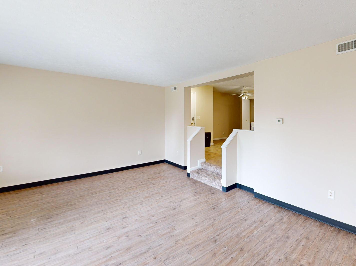Modern kitchen with stainless steel appliances, a breakfast bar, and white bar stools.