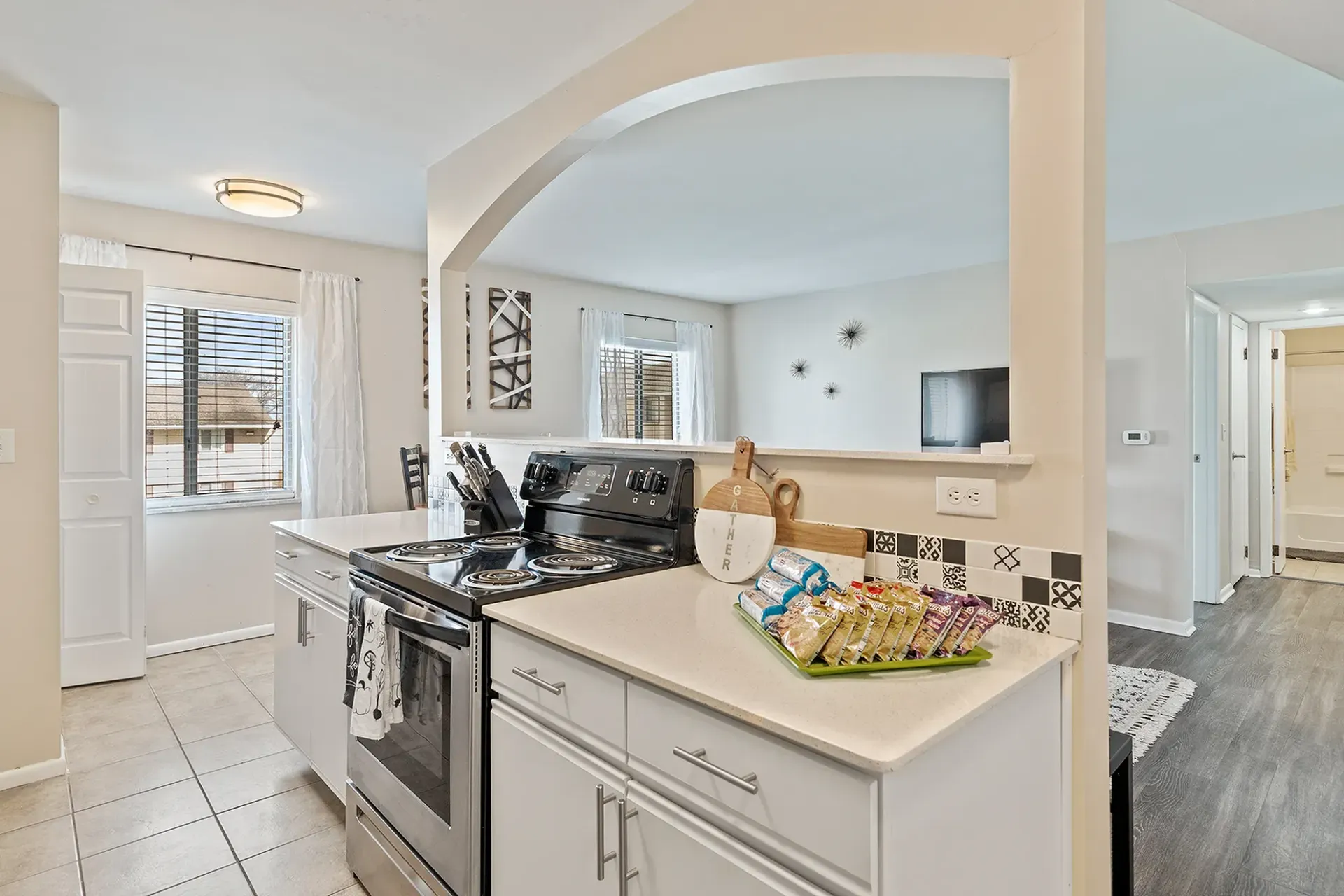 Kitchen with white cabinets, stainless steel appliances, and an archway leading to another room.
