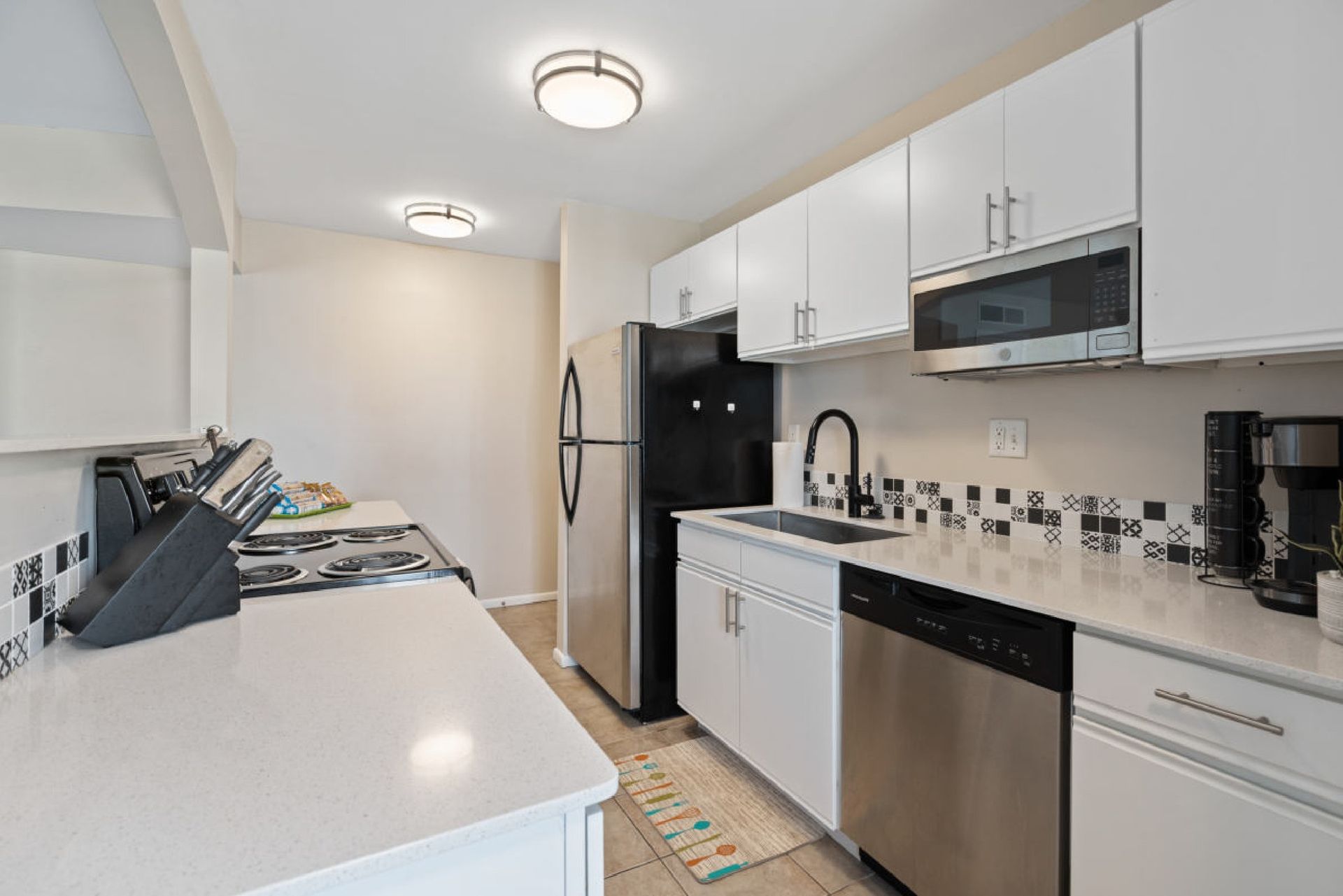 White kitchen with stainless steel appliances and black accents.