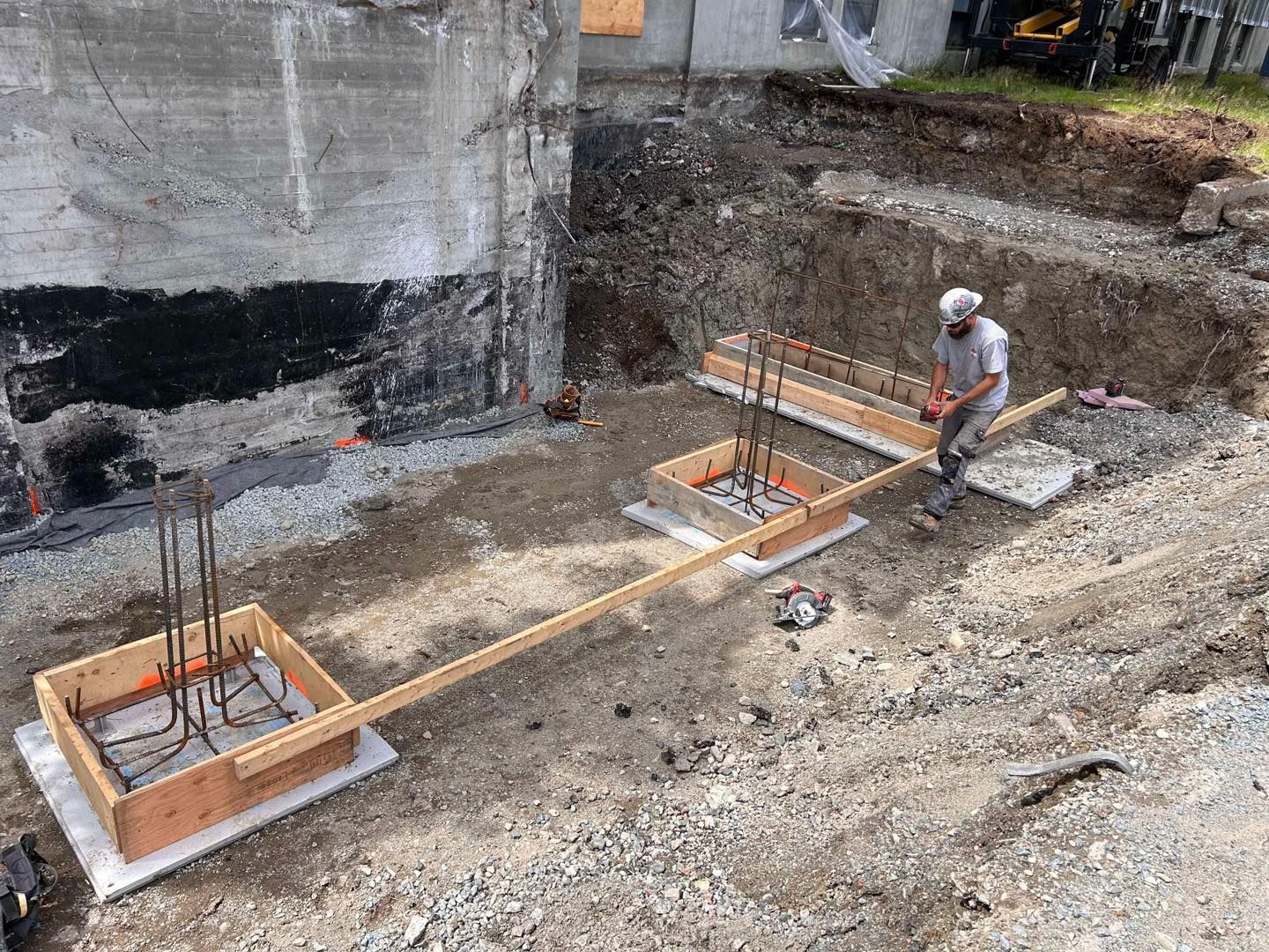 Un homme se tient debout dans un champ de terre tenant un bâton en bois.