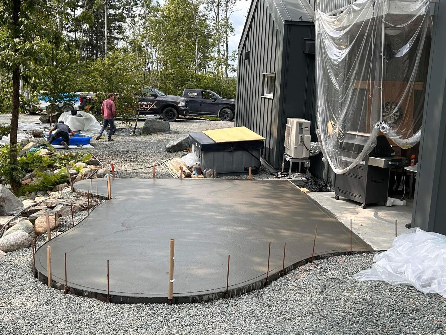 Une grande dalle de béton est en cours de construction devant une maison.