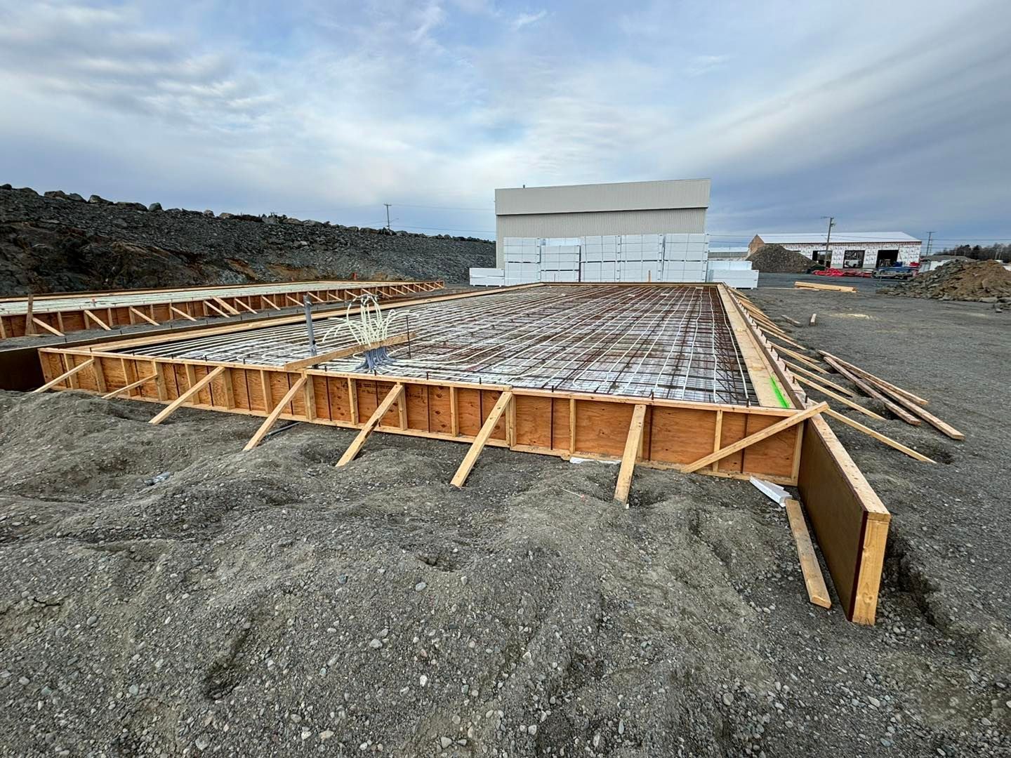 Une fondation en béton est en cours de construction dans un champ de terre.