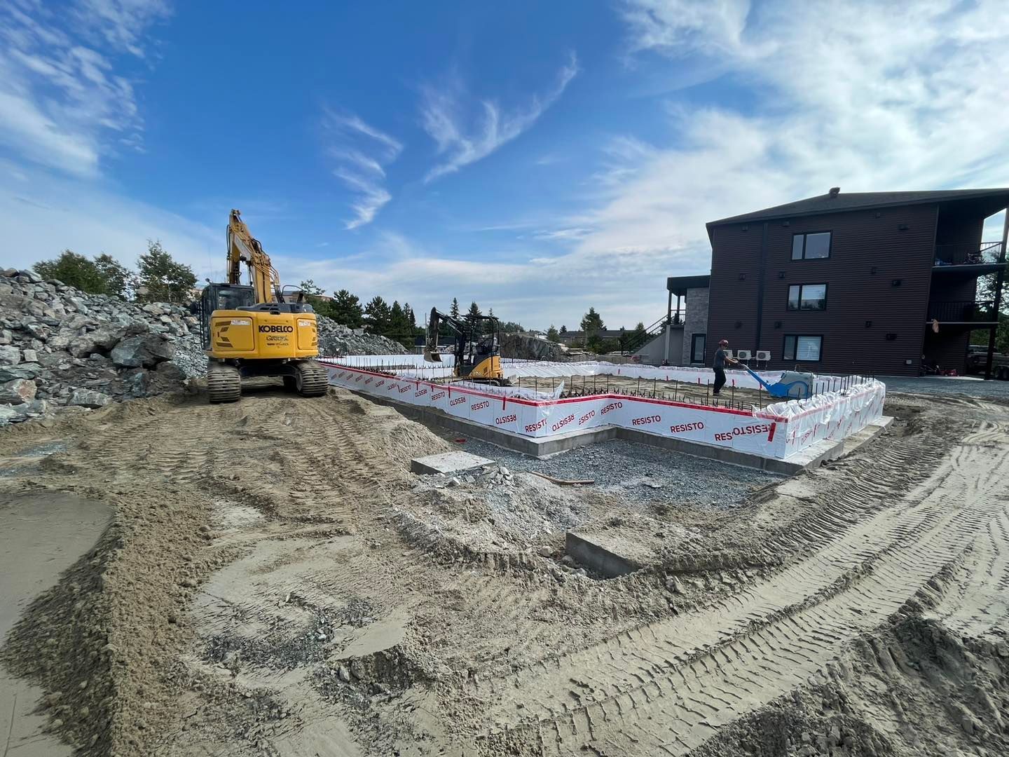 Un chantier de construction avec un bulldozer et un bâtiment en arrière-plan.