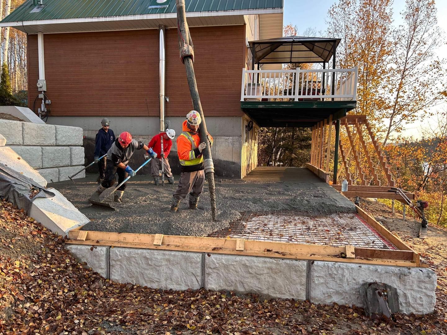 Un groupe d'ouvriers du bâtiment coule du béton devant une maison.