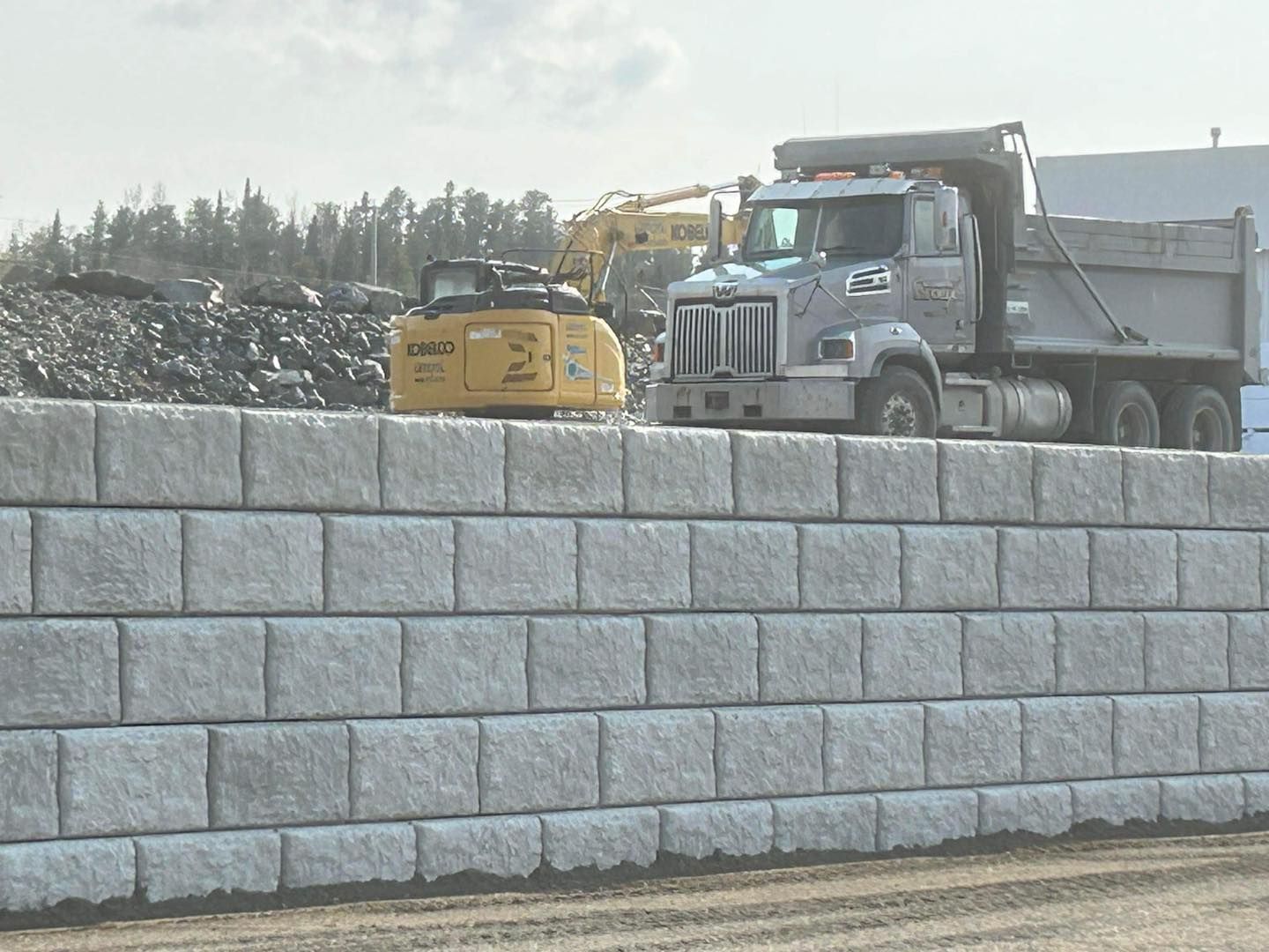 Un camion à benne basculante est garé à côté d'un mur de briques