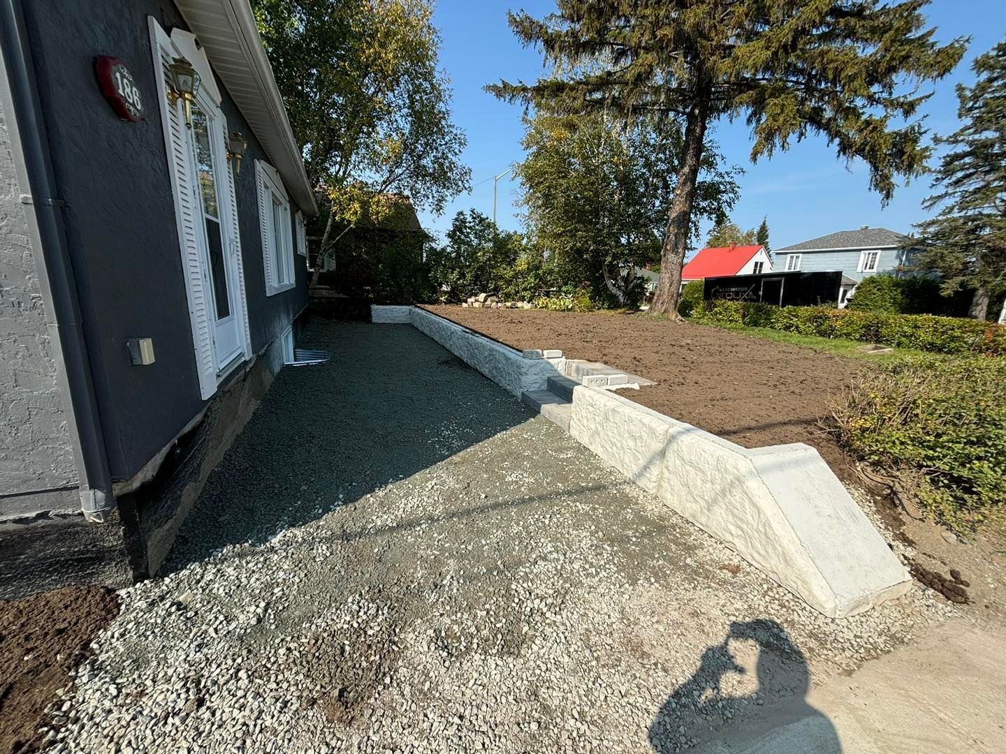 L'ombre d'une personne est projetée sur un chemin de gravier devant une maison.