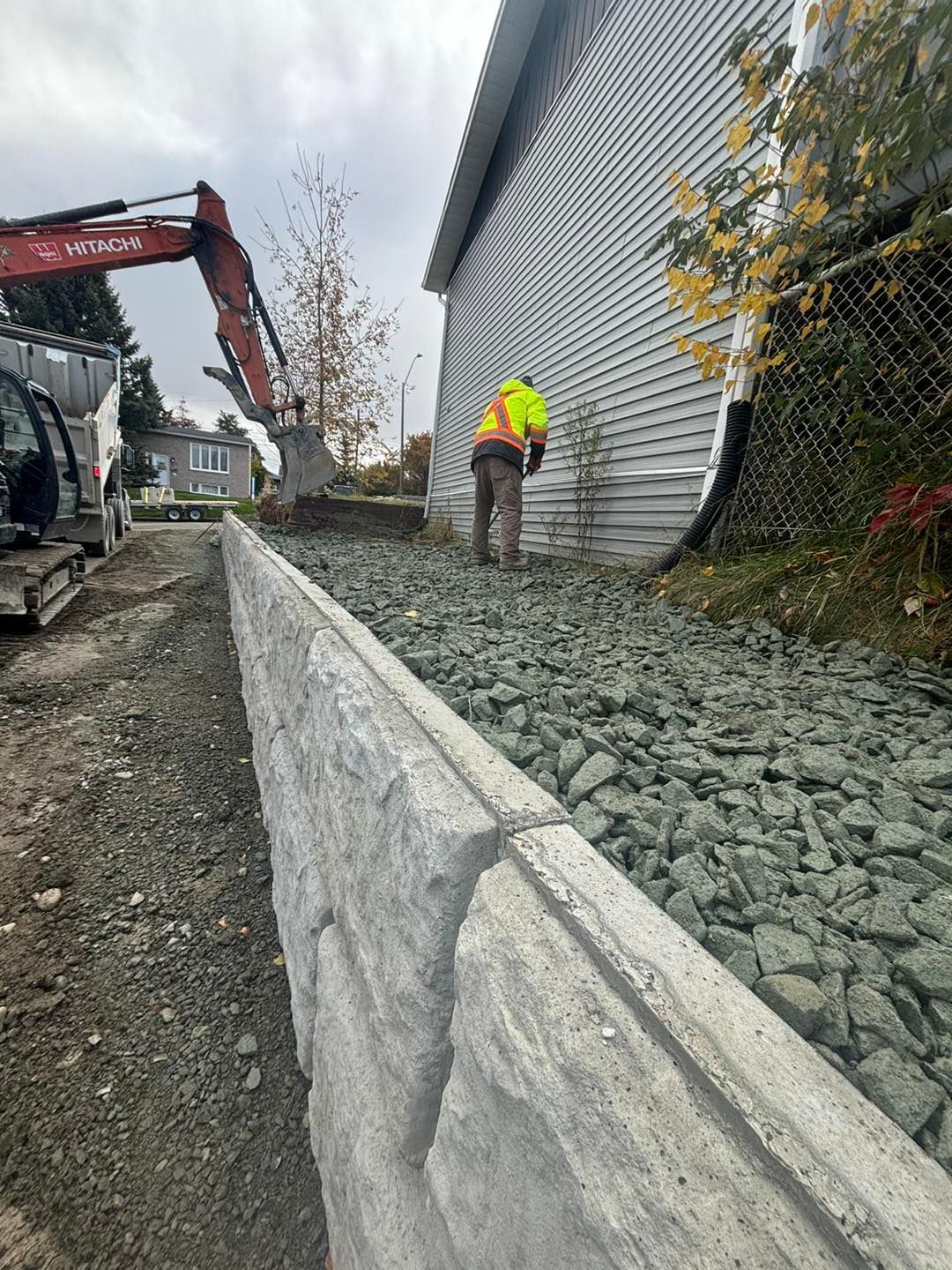 Un homme se tient debout sur un tas de gravier à côté d'un bâtiment.