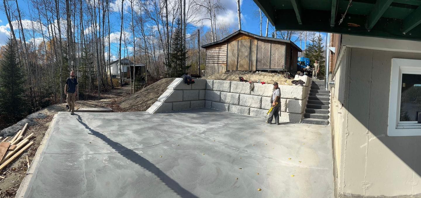 Un homme se tient sur une allée en béton à côté d'une maison.
