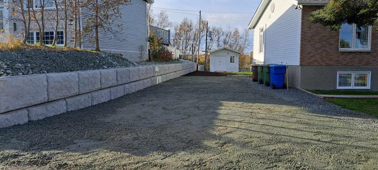 Une allée de gravier menant à une maison avec un mur de briques.
