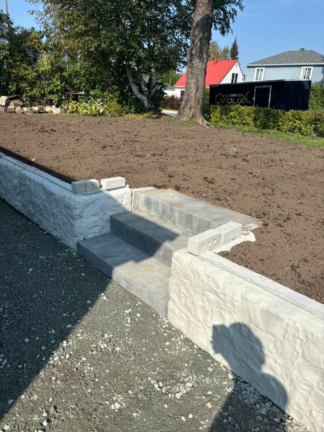 Un mur en béton avec des escaliers menant à un terrain en terre.
