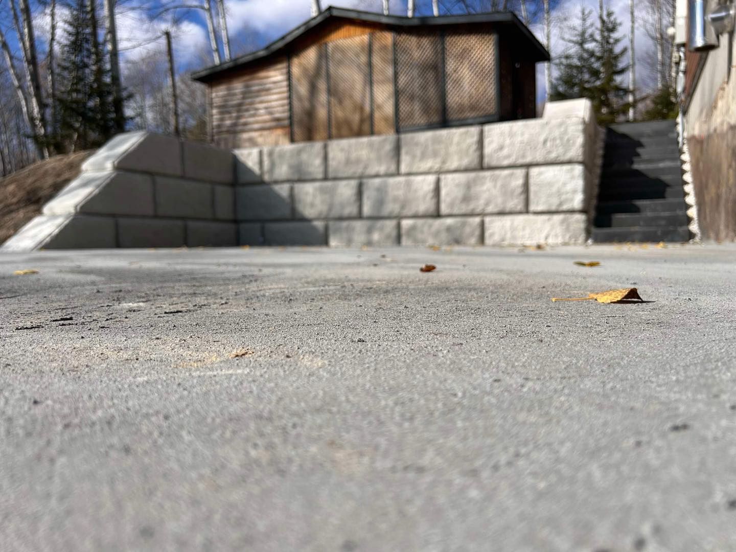Un mur en béton avec un hangar en bois en arrière-plan.