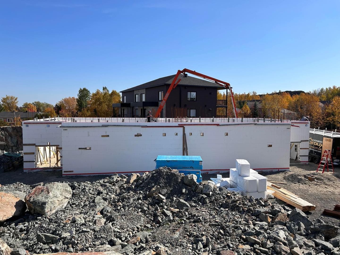 Un bâtiment en construction avec une pompe à béton en arrière-plan