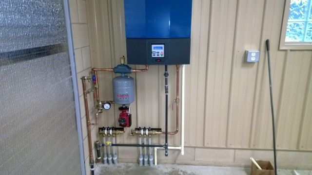 A room with a lot of pipes and a blue box on the wall.