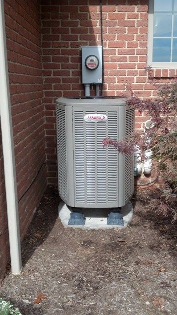 A lennox air conditioner is sitting outside of a brick building