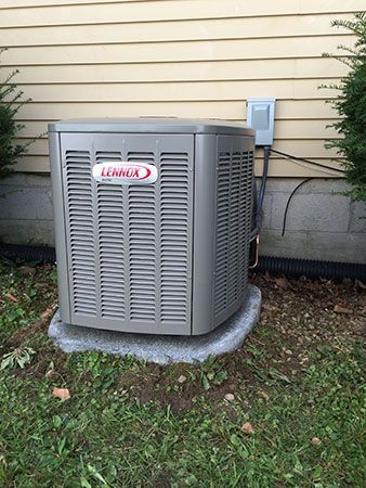 A lennox air conditioner is sitting in the grass next to a house.