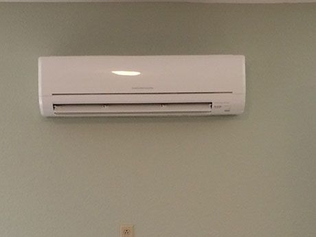 A white air conditioner is hanging on a wall in a room.