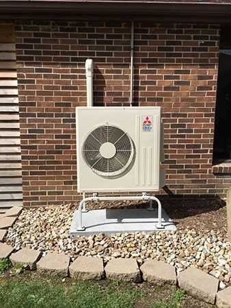 A mitsubishi air conditioner is installed on the side of a brick house.