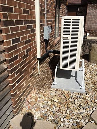 A white air conditioner is sitting outside of a brick building.