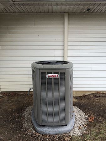 A lennox air conditioner is sitting outside of a house.