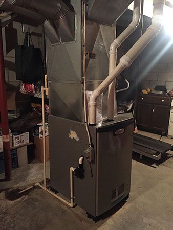 An air conditioner is sitting in a basement next to a treadmill.