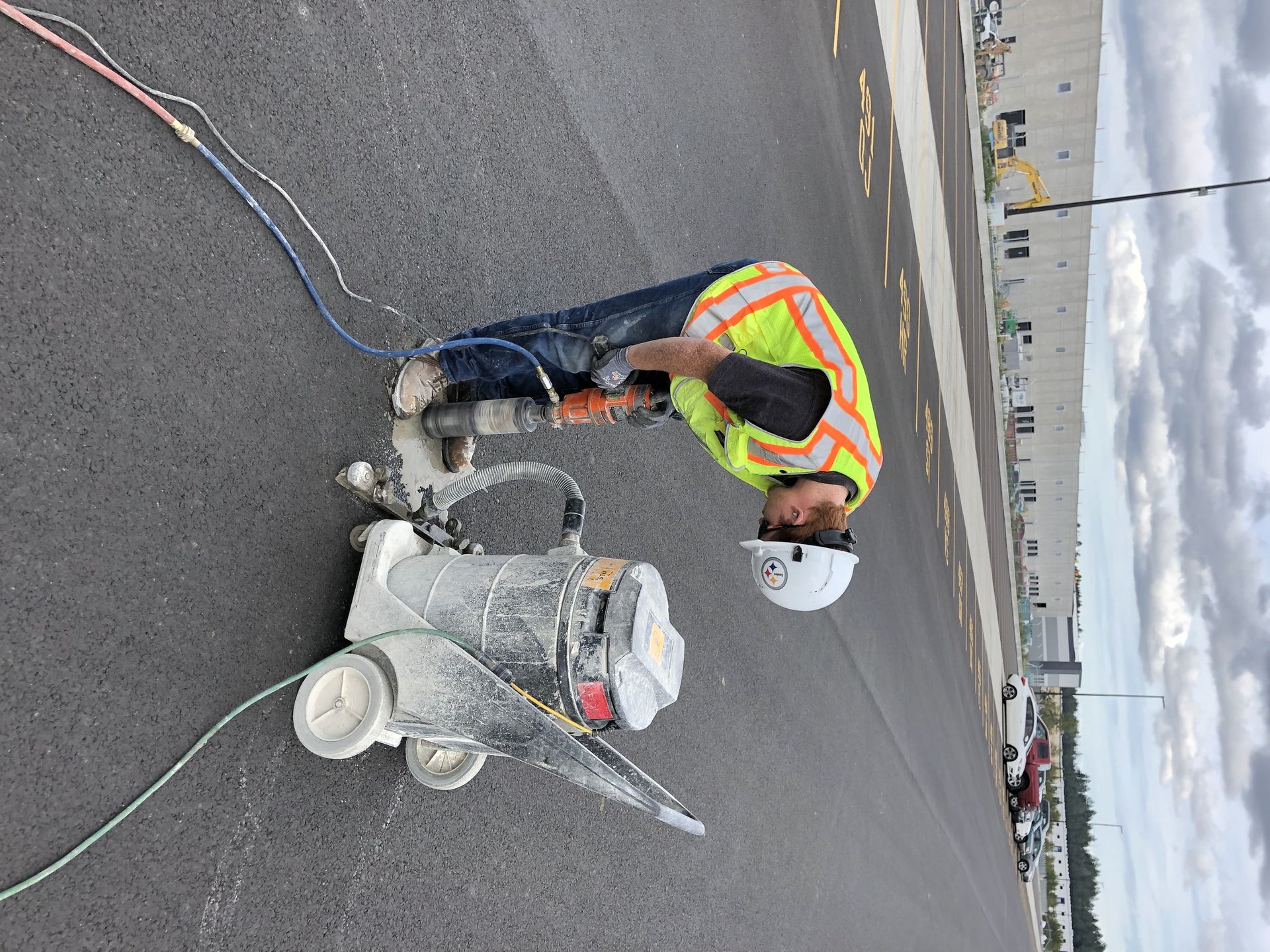 A man is cutting a hole in the road with a machine.