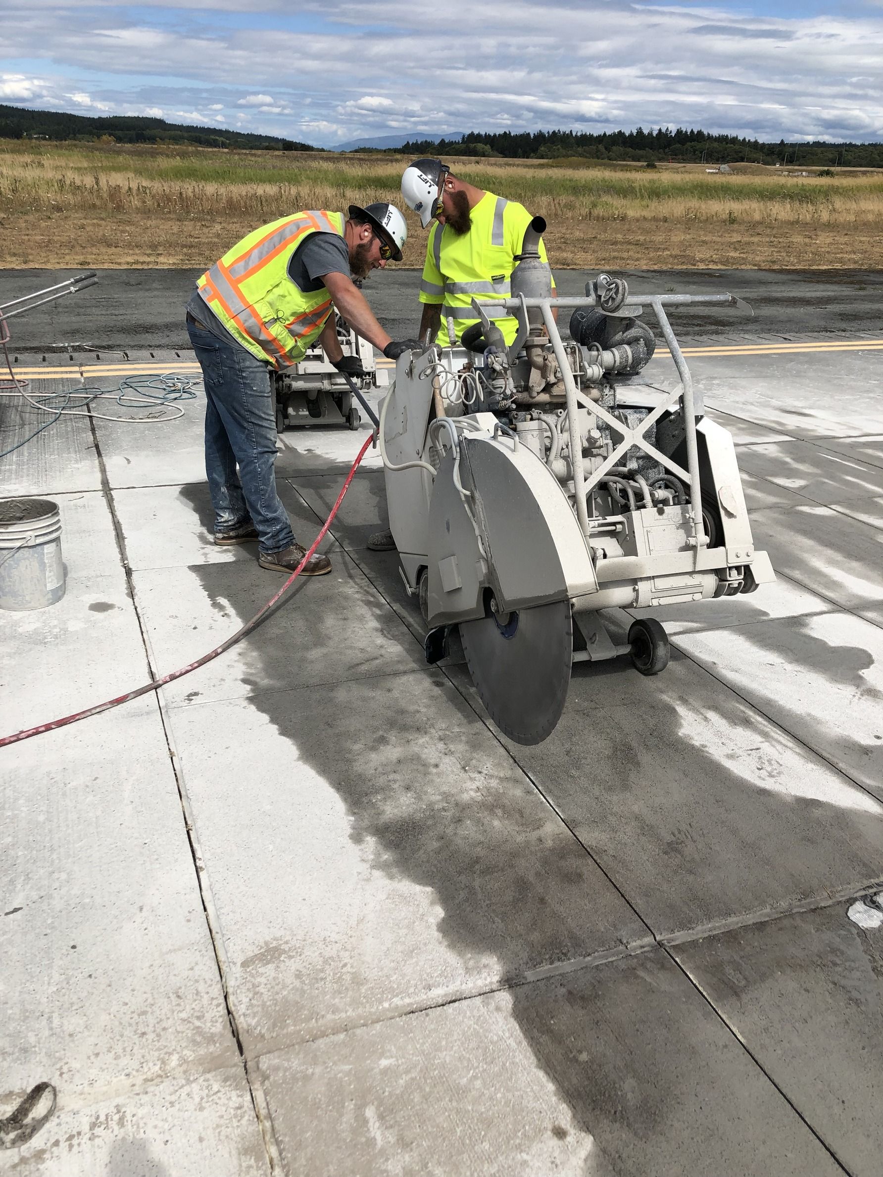 Two construction workers are cutting concrete with a circular saw.