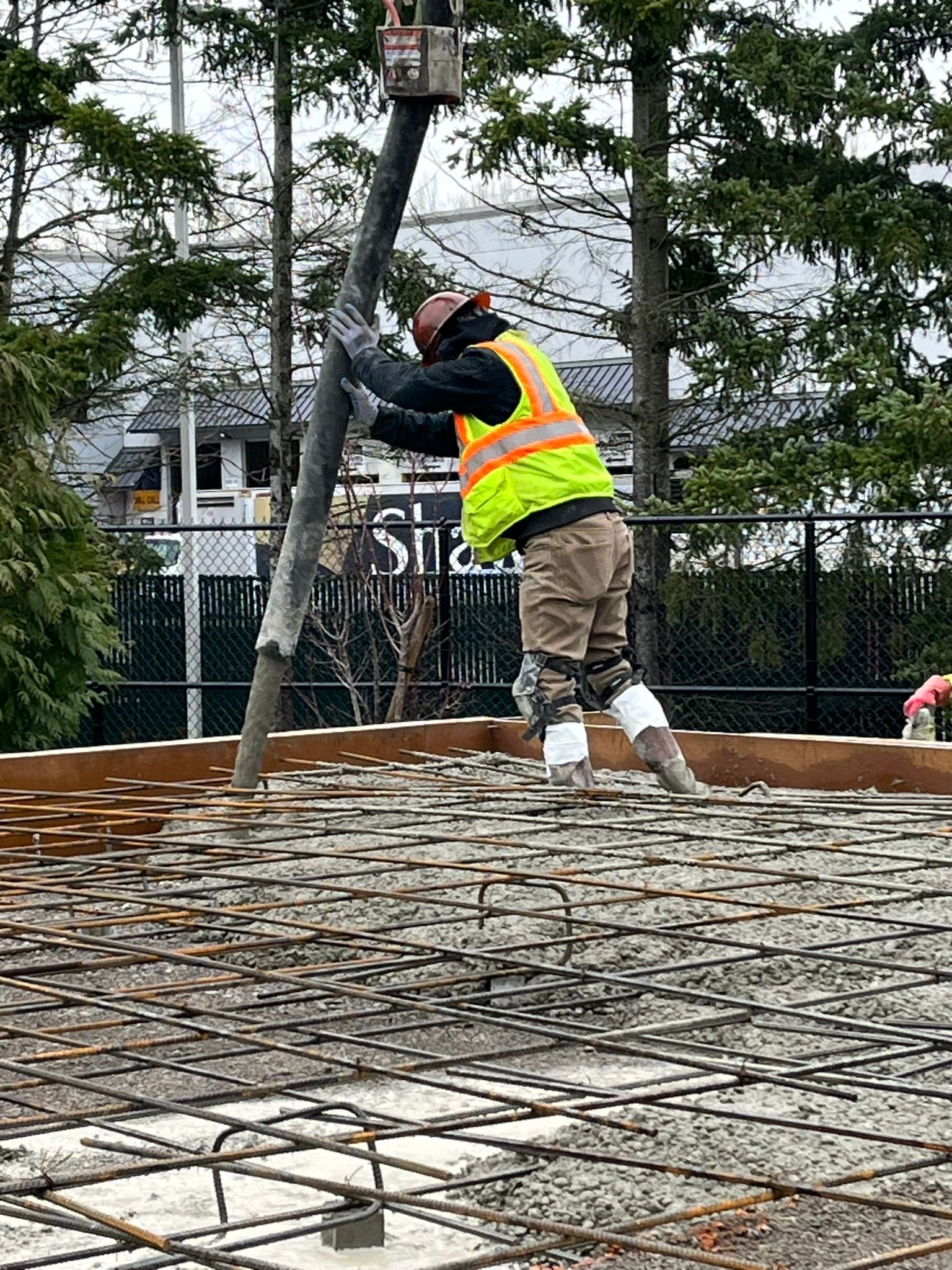A construction worker is pumping concrete into a concrete slab.