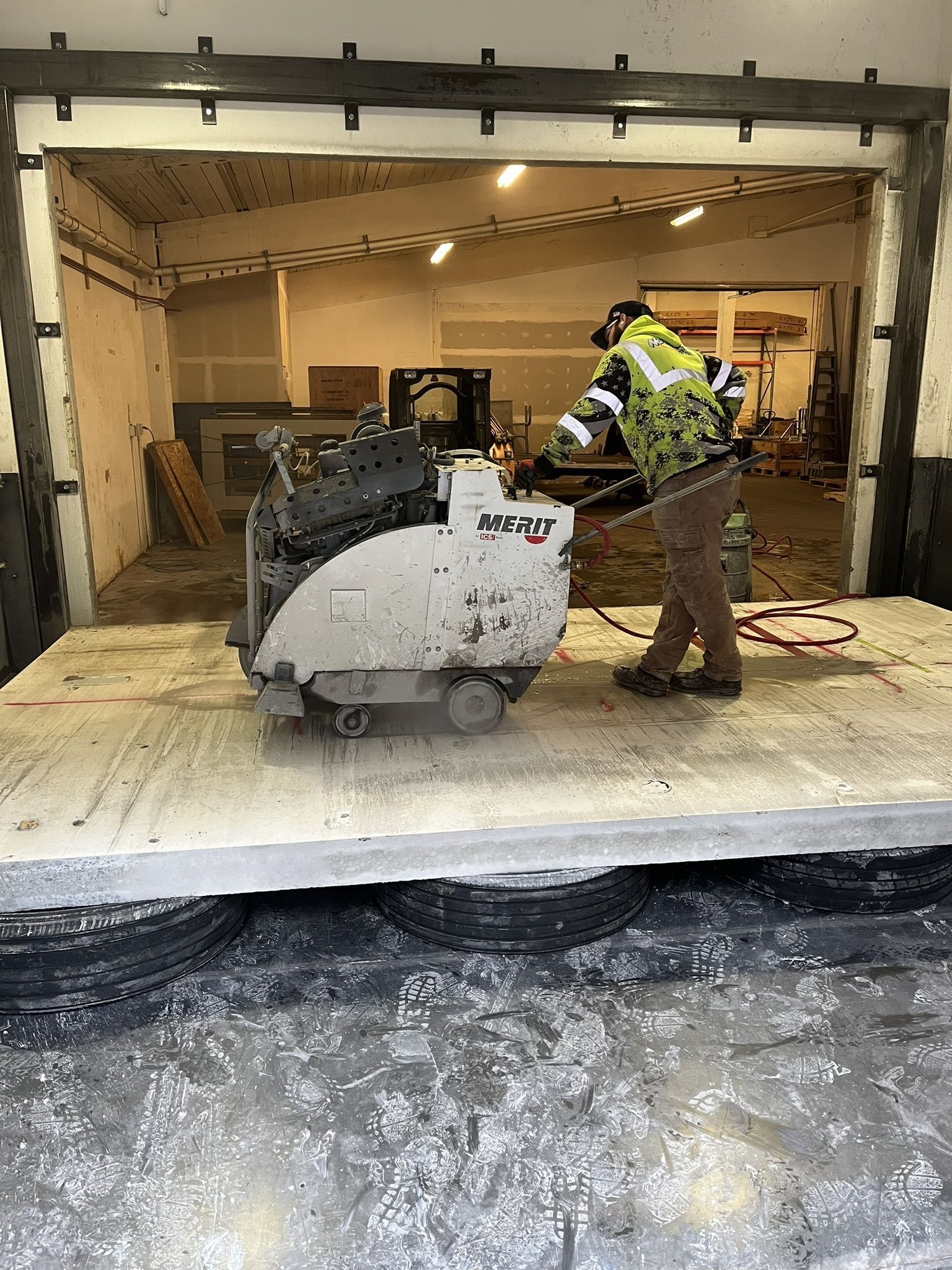 A man is using a concrete saw to cut a large piece of concrete.