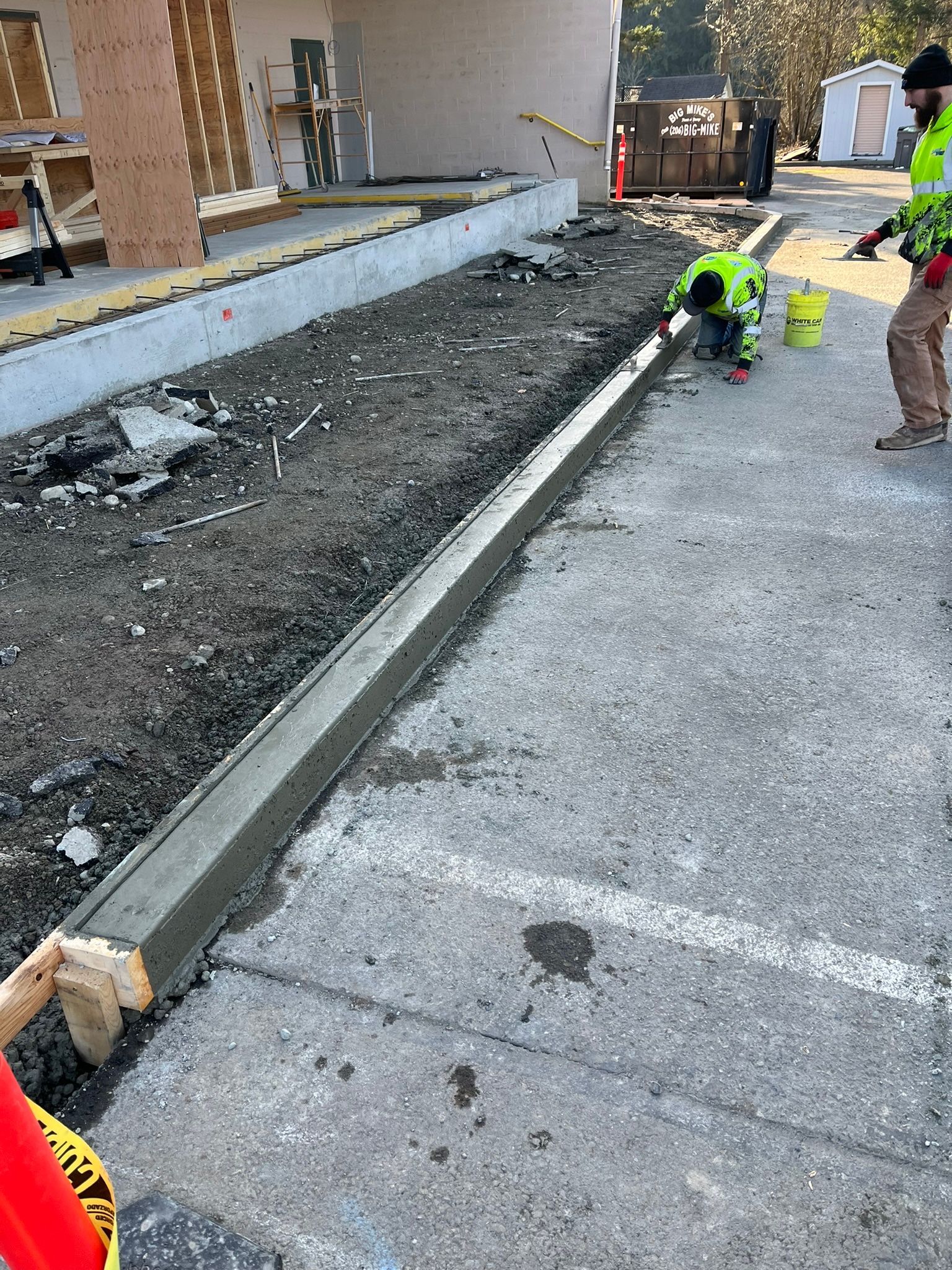 A group of construction workers are working on a sidewalk.